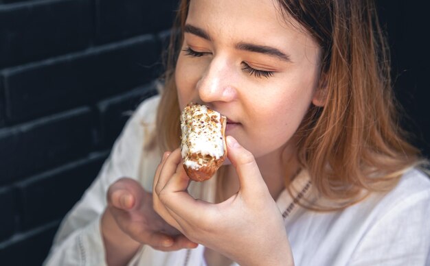 Een jonge vrouw eet een smakelijke eclair