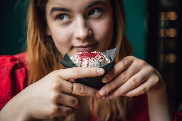 Een jonge vrouw geniet van een frambozenmuffin in een café