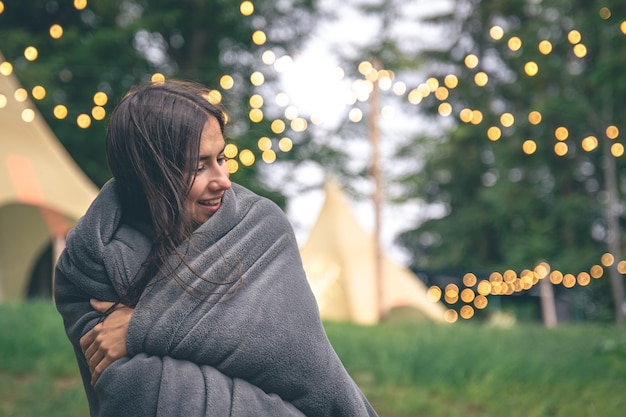 Een jonge vrouw gewikkeld in een deken in het bos op een onscherpe achtergrond