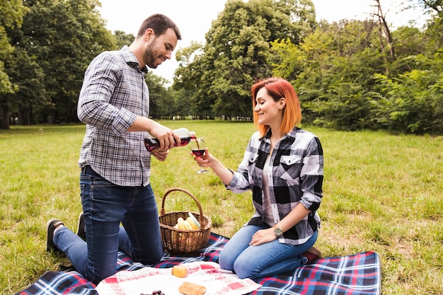 Gratis foto een jonge vrouw gieten wijn in glazen greep door haar vrouw op picknick in het park