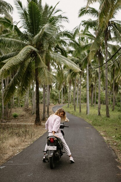 Een jonge vrouw in de jungle rijdt op een scooter