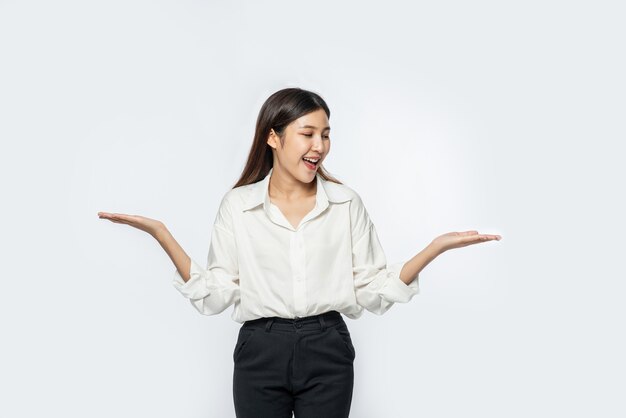 Een jonge vrouw in een wit overhemd en beide handen spreidend