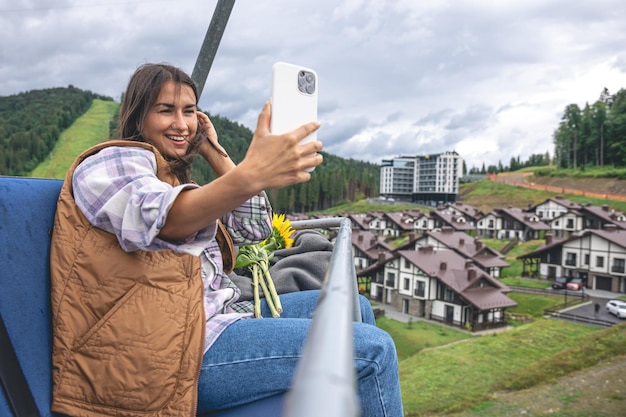 Een jonge vrouw maakt een selfie op een kabelbaan in de bergen