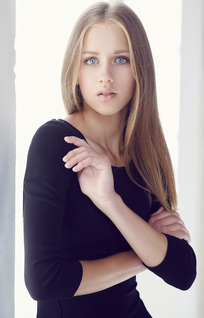 Een jonge vrouw met blauwe ogen in een zwarte jurk met gekruiste armen.