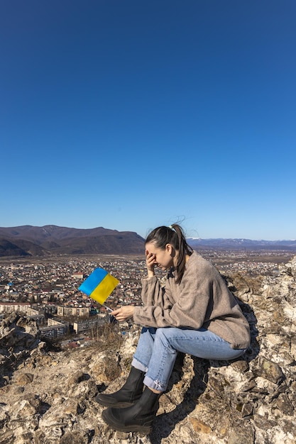 Een jonge vrouw met de vlag van Oekraïne op de achtergrond van het stadslandschap