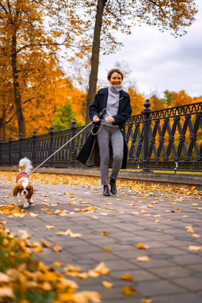 Een jonge vrouw met een hond loopt in het herfstpark