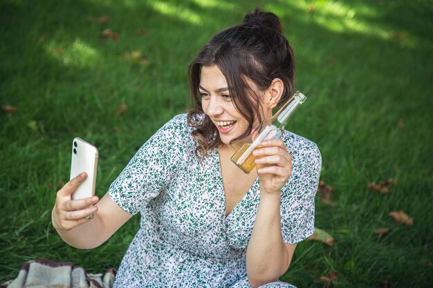 Een jonge vrouw op een picknick maakt een selfie met een fles drank
