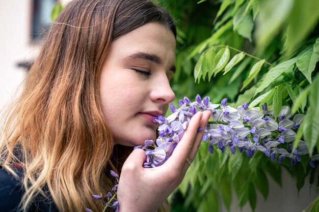 Een jonge vrouw ruikt een blauweregenbloem