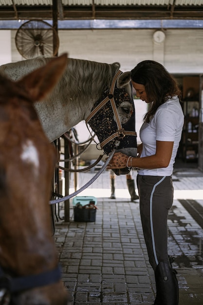 Een jonge vrouw voert wortelen aan een paard.