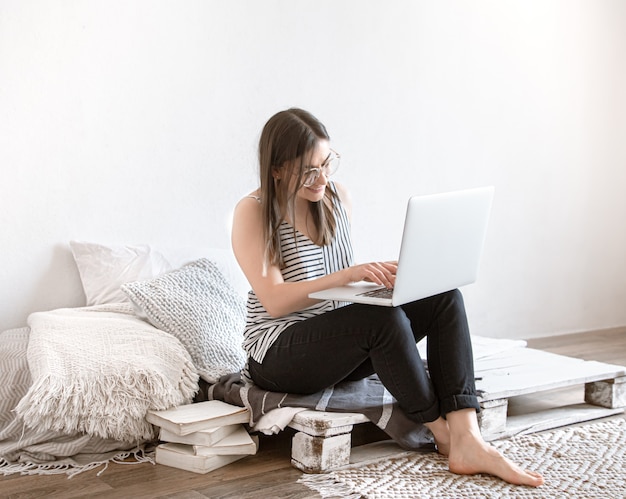 Een jonge vrouw werkt thuis op afstand op een computer. Freelancer en werk op internet.