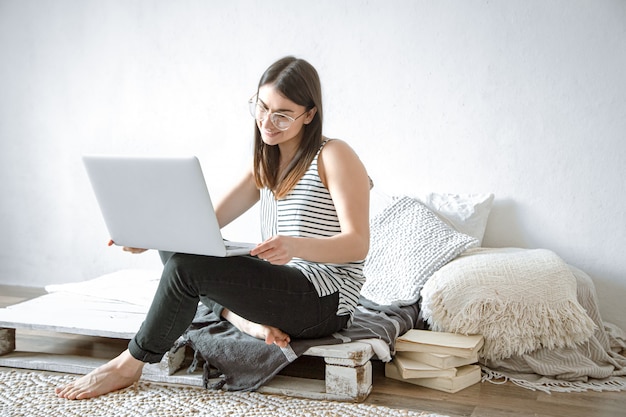 Een jonge vrouw werkt thuis op afstand op een computer. Freelancer en werk op internet.