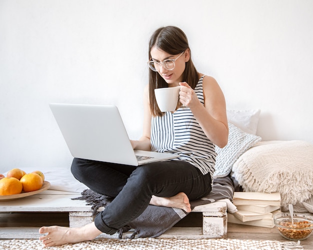 Een jonge vrouw werkt thuis op afstand op een computer.