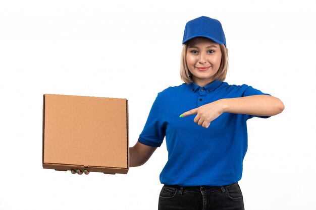 Een jonge vrouwelijke koerier vooraanzicht in blauw uniform de leveringspakket van het holdingsvoedsel met glimlach op haar gezicht