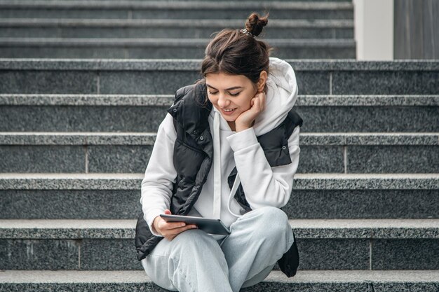 Een jonge vrouwelijke student staat buiten met een digitale tablet in haar handen