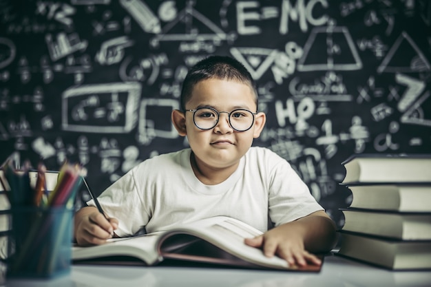 Een jongen met een brilmens die in de klas schrijft