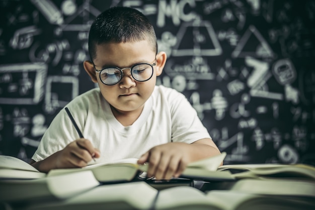 Een jongen met een brilmens die in de klas schrijft