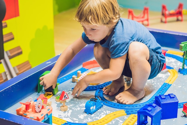 Een jongen speelt met een stuk speelgoed spoorweg.