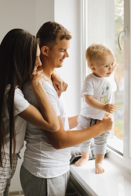 Een jongetje kijkt in het raam en zijn ouders bewonderen hem