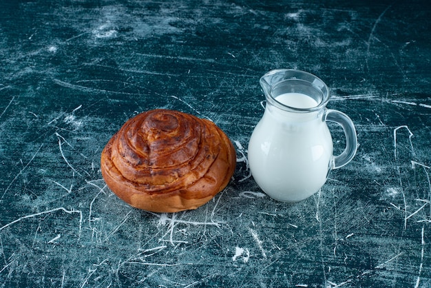 Een kaneelbroodje met een potje melk opzij.