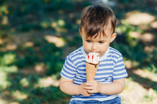 Een kind in een t-shirt op een bankje dat ijs eet in de zomer erg warm en lekker