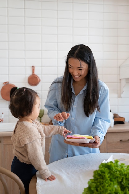 Een klein Aziatisch meisje dat thuis met haar moeder in de keuken doorbrengt