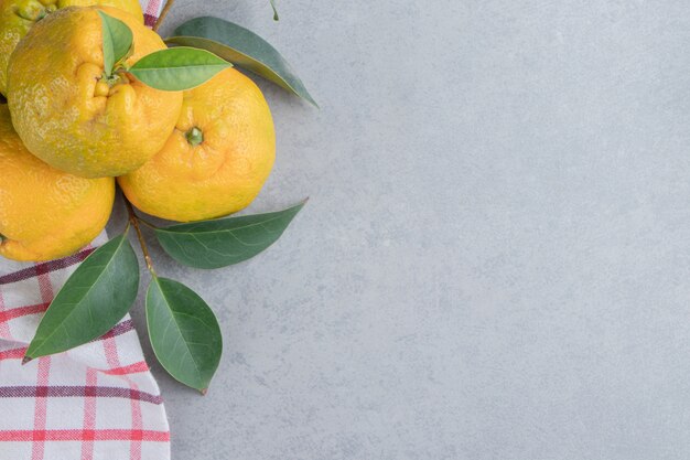 Een klein bundeltje mandarijnen op een handdoek op marmer.