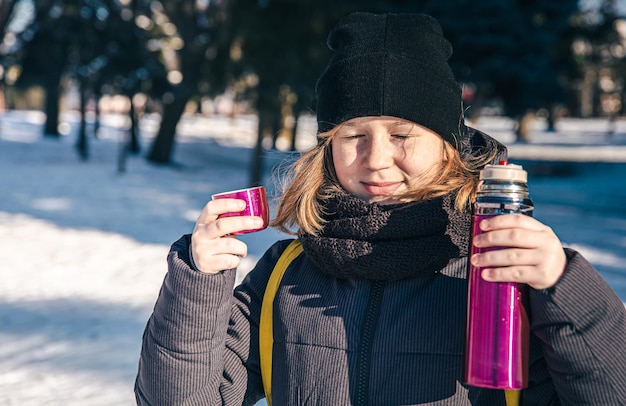 Een klein meisje buiten met thermoskan op een koude winterdag