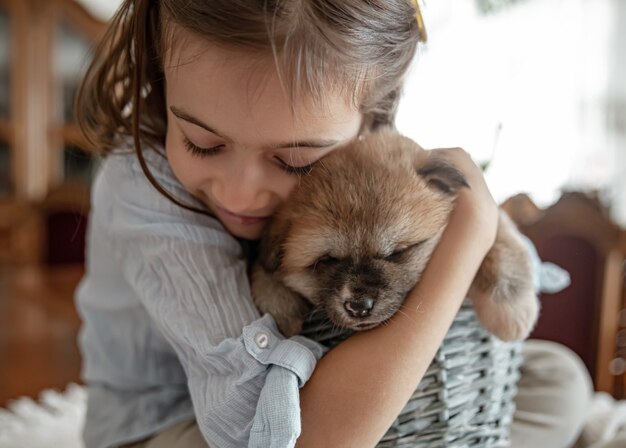 Een klein meisje houdt van en knuffelt haar kleine puppy