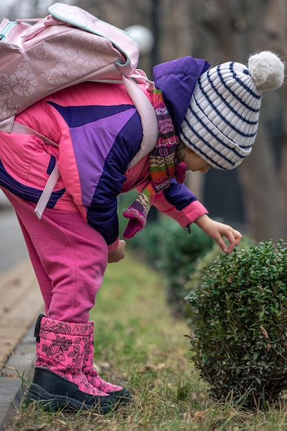 Een klein meisje kijkt naar de bladeren buiten het koude seizoen