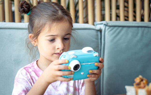 Een klein meisje met een digitale speelgoedcamera voor kinderen om direct foto's te printen.