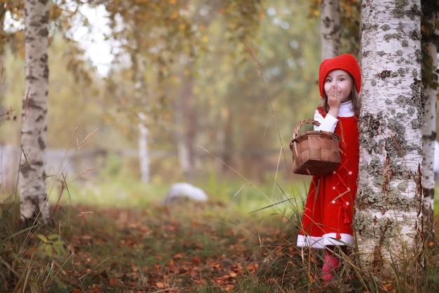 Een klein meisje met een rode hoed en jurken loopt in het park. cosplay voor de sprookjesheld 