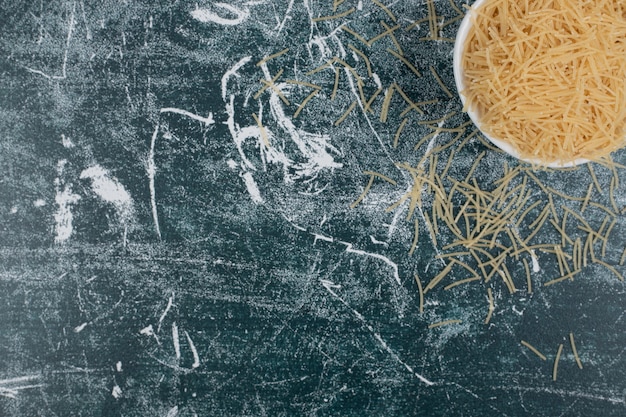 Gratis foto een klein wit bord met onbereide vermicelli op marmeren achtergrond. hoge kwaliteit foto