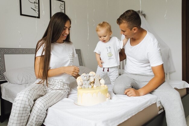 Een kleine jongen verheugt zich over de verjaardagstaart van zijn ouders