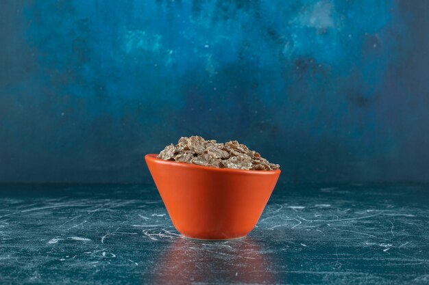 Een kleine portie droge cornflakes, op de blauwe achtergrond. Hoge kwaliteit foto