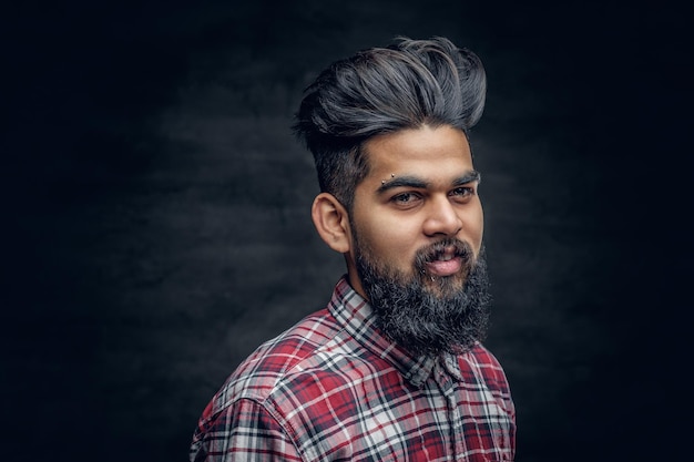 Een knappe bebaarde Indiase man gekleed in een fleece shirt over grijze vignet achtergrond.