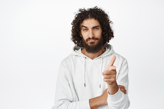 Een knappe man uit het Midden-Pasen die met de vinger naar de camera wijst met een zelfverzekerde blik die je uitnodigt om mensen te rekruteren die op een witte achtergrond staan