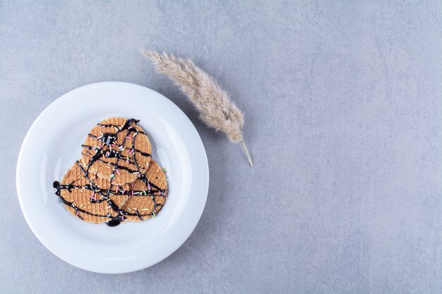 Een koekenpan van ronde rossige wafel met hagelslag en room.