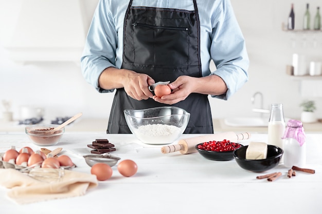 Een kok op een rustieke keuken. De mannelijke handen met ingrediënten voor het koken van meelproducten of deeg, brood, muffins, taart, cake, pizza