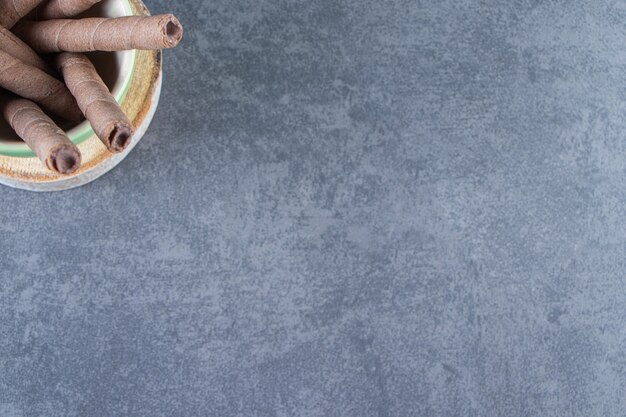 Een kom chocoladewafel rolt op een bord op het marmeren oppervlak