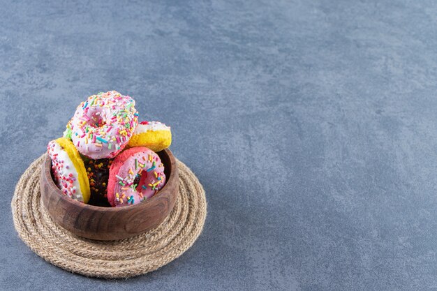 Een kom donuts op een onderzetter op het marmeren oppervlak