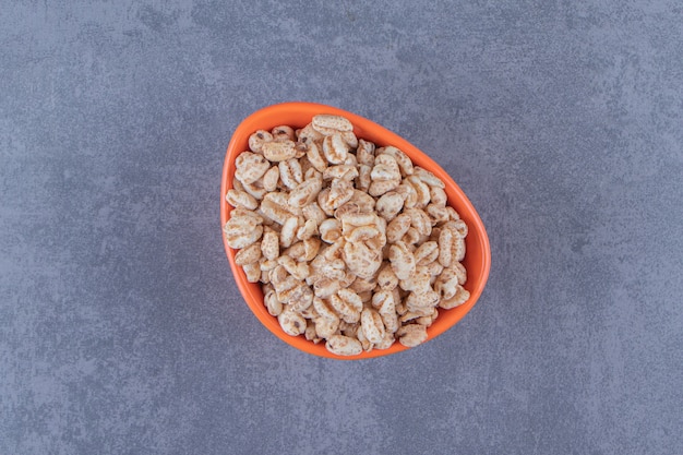 Een kom droge cornflakes, op de blauwe achtergrond. Hoge kwaliteit foto