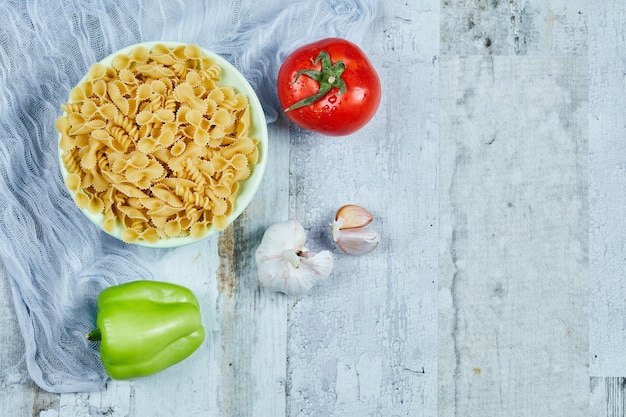 Een kom rauwe pasta met tomaat, peper en knoflook.