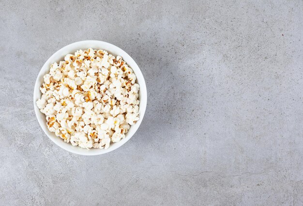 Een kom vol knapperige popcorn op marmeren achtergrond. Hoge kwaliteit foto