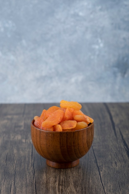 Een kom vol met gezonde gedroogde abrikozenvruchten op een houten tafel.