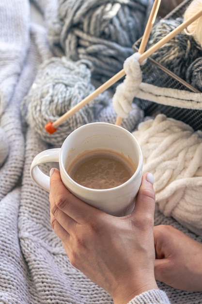 Een kop koffie in vrouwelijke handen en een draad van garen