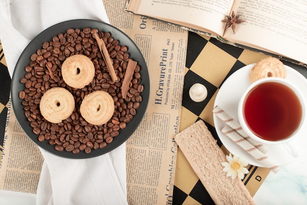 Een kop thee en koffiebonen met koekjes