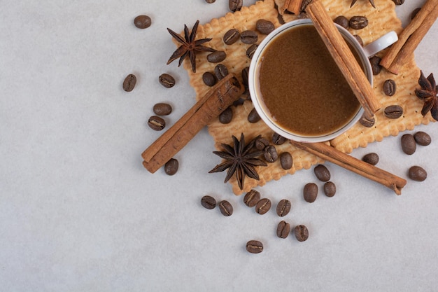 Een kop warme koffie met steranijs en kaneelstokjes op crackers. hoge kwaliteit foto