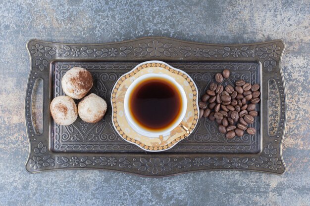 Een kopje donkere koffie met koekje op donker bord. Hoge kwaliteit foto