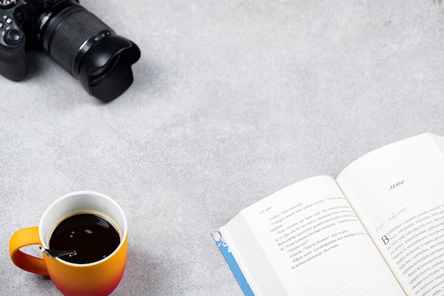 Een kopje espresso met een boek en fotocamera op tafel