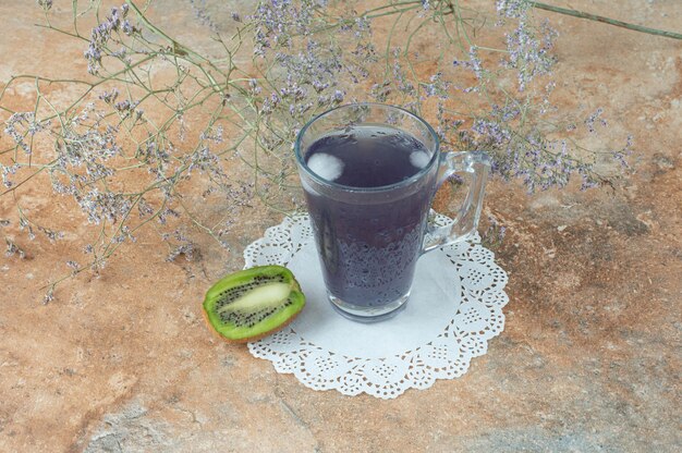 Een kopje heerlijke drank met plakje kiwi op marmeren tafel.